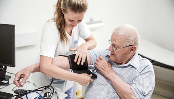 Elderly man get a heart rate check with the assistance of female nurse