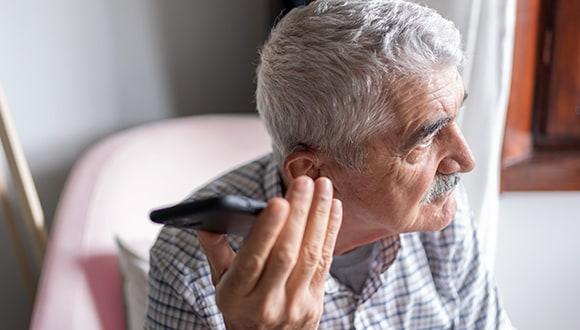 A man listening to his phone on speakerphone