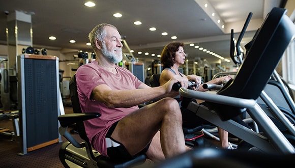 Elderly man using exercise equipment at the gym