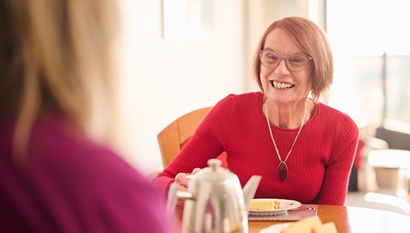 Woman sitting at a table with a carer, smiling