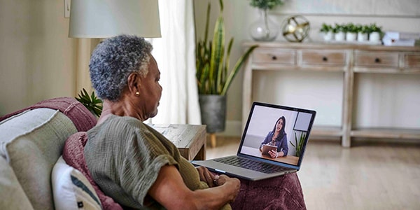 A woman sits on a couch using her laptop