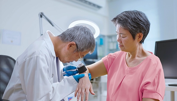 A skin specialist examines a woman's arm