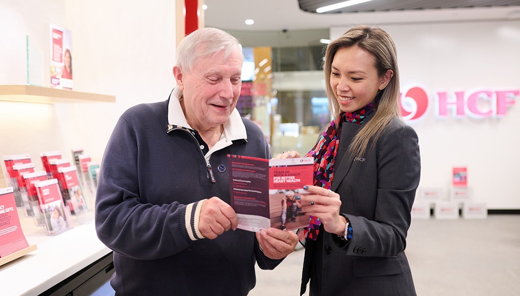 HCF staff assisting an older man with his private health insurance.