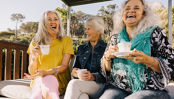 3 older ladies laughing and smiling and connecting together socially