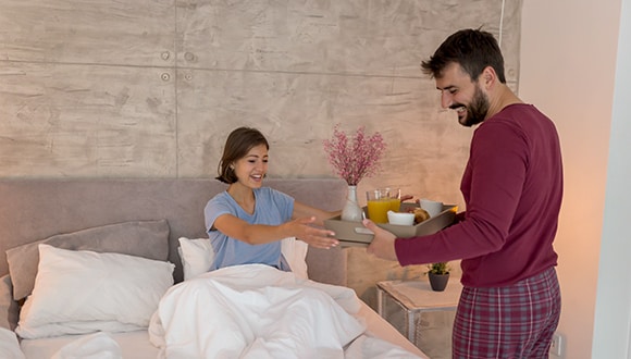 Man delivering woman breakfast in bed