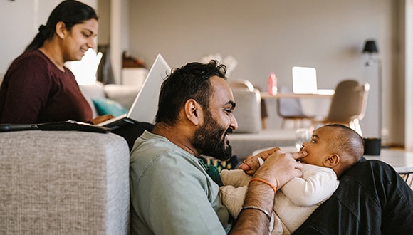 Man playing with child while wife researching life insurance options
