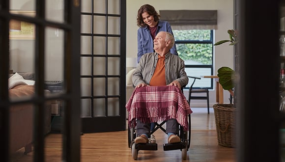 Female carer pushing an elderly man in a wheelchair
