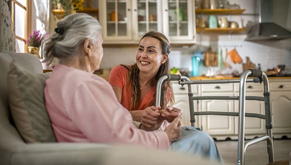 elderly woman sitting on a couch speaking to a female carer