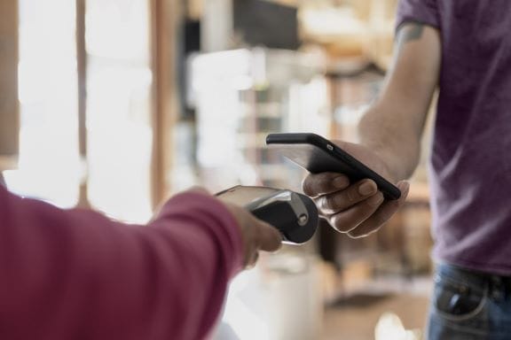 A person making a cashless payment at a shop with their smart phone.