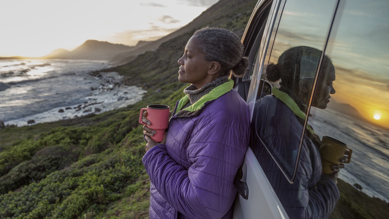 A lady enjoying a coffee while beachside.
