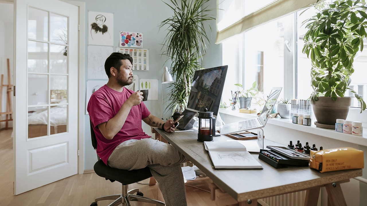 A man sits at a desk in his home working on his computer.