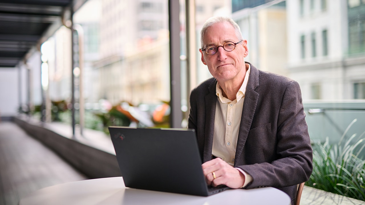 Professor Ian Harris sits at a bench with a laptop.