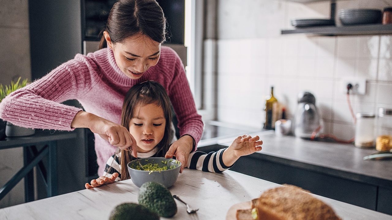 Mother and daughter cooking food together in the kitchen.