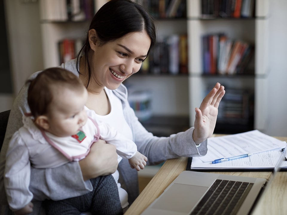 Mother sitting with her baby in front of the laptop.