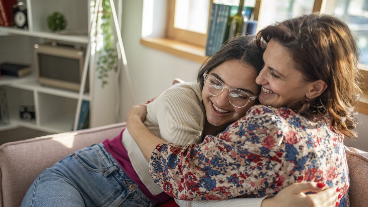 A mother and daughter hugging on the lounge.