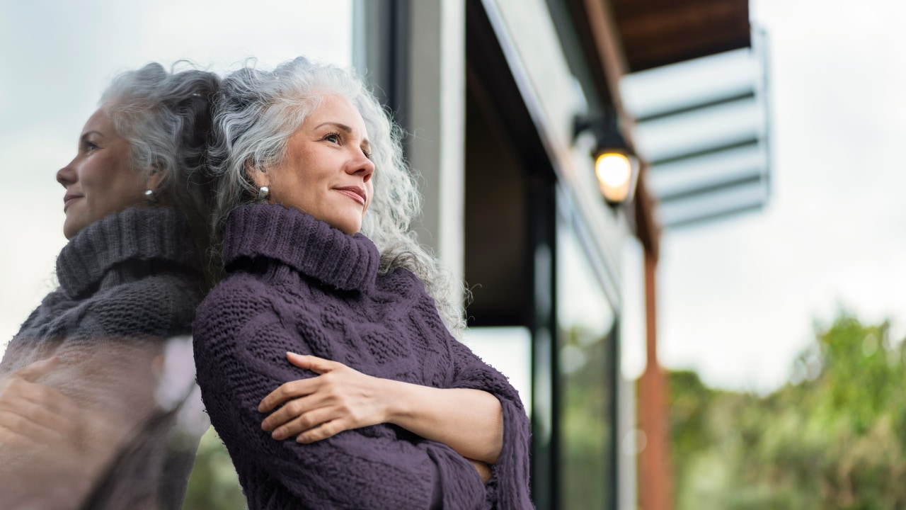 Woman leaning against glass wall looking out.