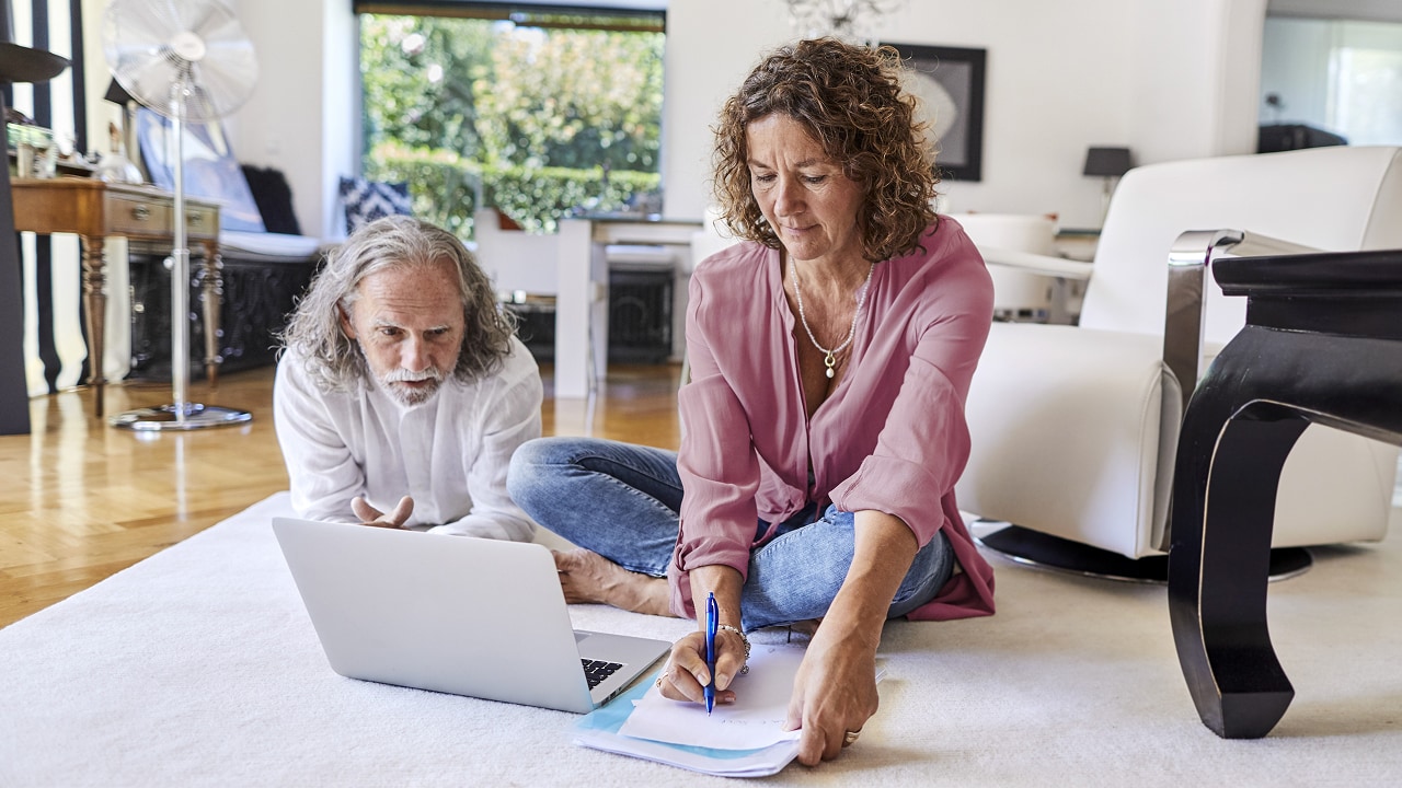 A man and woman on the ground working off a laptop.