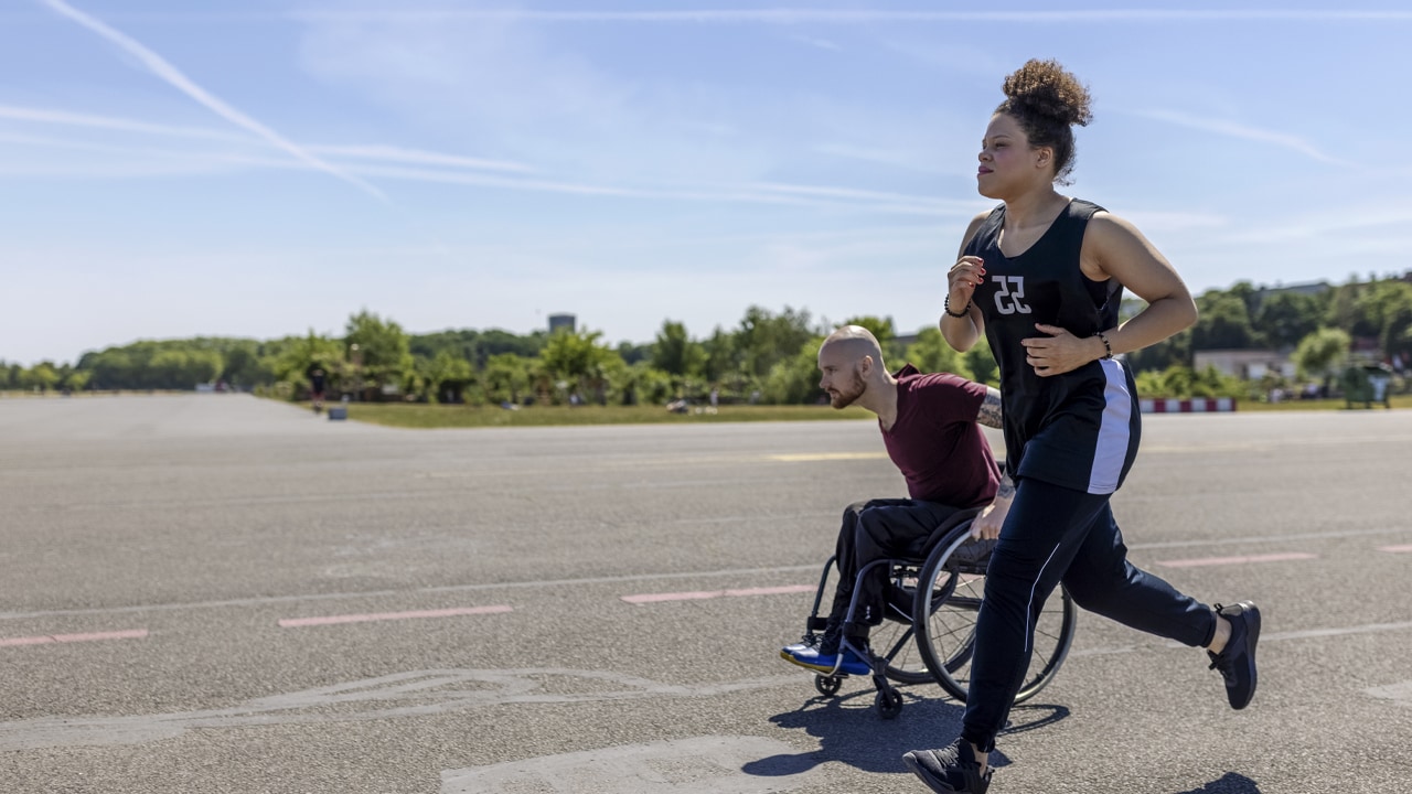 A man in a wheelchair trains with a woman.