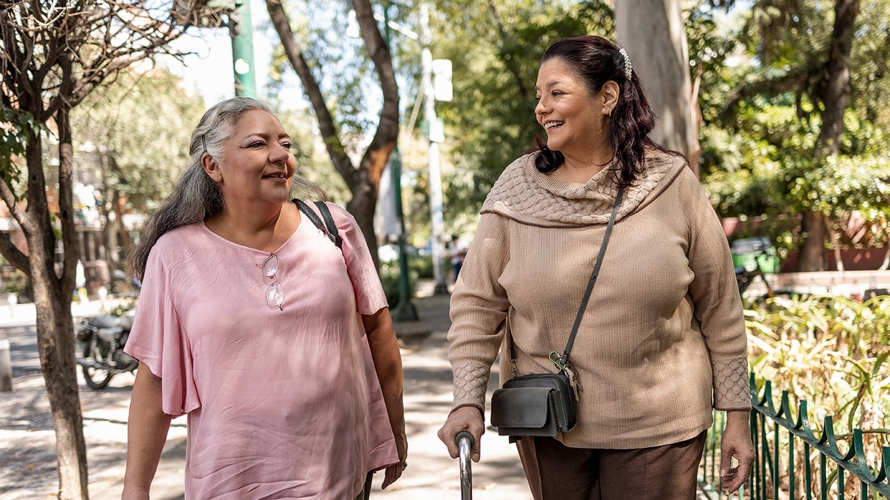 A woman walking with her elderly mother outdoors.