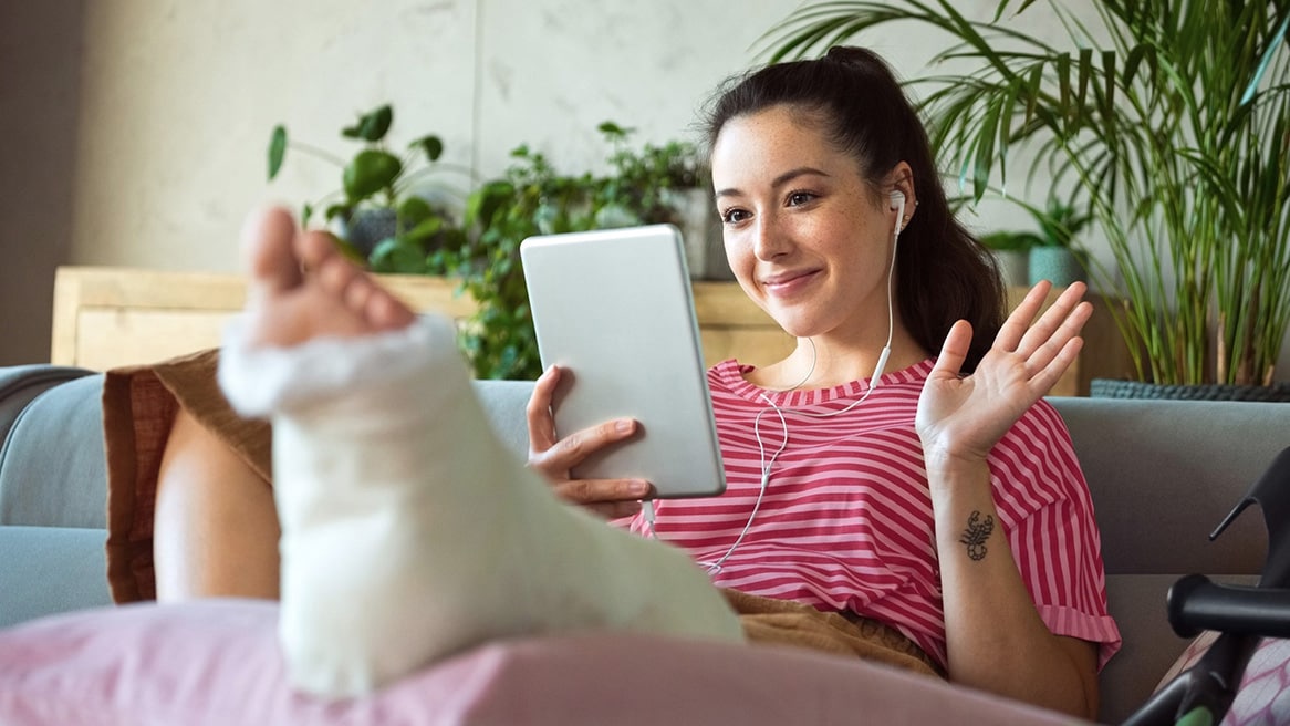 A woman sitting on the lounge with a broken leg.